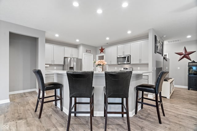13321 N White Cloud Ct, Camby, IN 46113 - kitchen featuring stainless steel appliances, baseboards, light wood-style floors, light countertops, and a center island