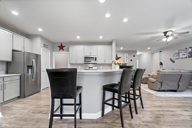13321 N White Cloud Ct, Camby, IN 46113 - kitchen featuring stainless steel appliances, a breakfast bar, light wood-type flooring, recessed lighting, and light countertops