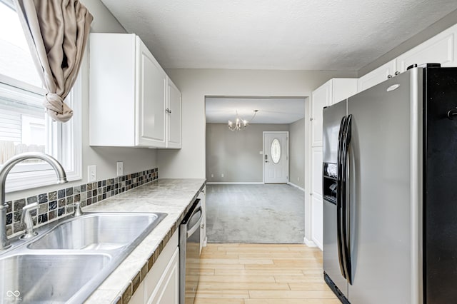148 S 3rd Ave, Beech Grove, IN 46107 - kitchen featuring stainless steel appliances, a sink, light wood-style flooring, white cabinets, and a chandelier