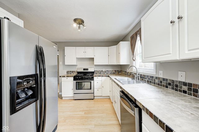 148 S 3rd Ave, Beech Grove, IN 46107 - kitchen featuring appliances with stainless steel finishes, a sink, light wood finished floors, and white cabinetry