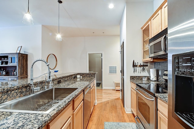 350 N Meridian St Unit A303, Indianapolis, IN 46204 - kitchen featuring appliances with stainless steel finishes, a sink, light wood-style flooring, decorative light fixtures, and light brown cabinets