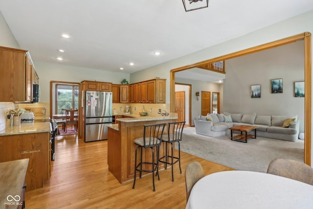 3564 Clear Creek Blvd, Martinsville, IN 46151 - kitchen featuring stainless steel appliances, open floor plan, a breakfast bar, light wood finished floors, and brown cabinetry