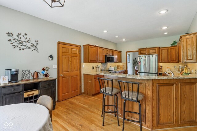 3564 Clear Creek Blvd, Martinsville, IN 46151 - kitchen with stainless steel appliances, backsplash, light wood-type flooring, brown cabinets, and light stone countertops