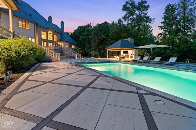 11101 Hawthorn Rdg, Fishers, IN 46037 - pool at dusk featuring stairs, a patio area, an outdoor structure, and an outdoor pool