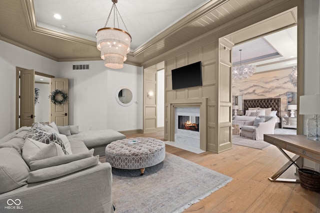 11101 Hawthorn Rdg, Fishers, IN 46037 - living area featuring a chandelier, light wood-style floors, crown molding, a high end fireplace, and a raised ceiling