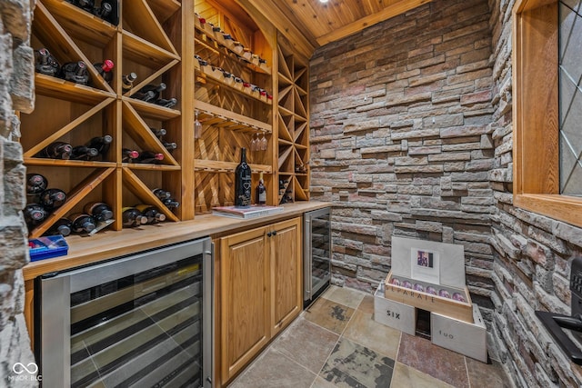11101 Hawthorn Rdg, Fishers, IN 46037 - wine cellar featuring wine cooler, wood ceiling, light stone finish flooring, and a bar