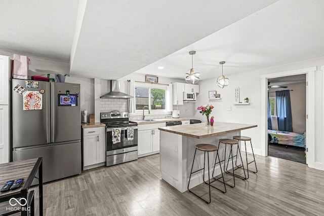 2 S 25th Ave, Beech Grove, IN 46107 - kitchen featuring stainless steel appliances, wall chimney exhaust hood, butcher block countertops, a kitchen breakfast bar, and light wood-type flooring
