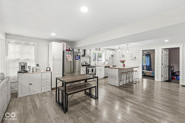 2 S 25th Ave, Beech Grove, IN 46107 - kitchen with appliances with stainless steel finishes, wall chimney range hood, white cabinetry, light wood-type flooring, and recessed lighting