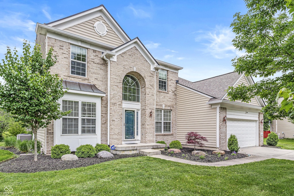 2070 Mustang Chase Dr, Carmel, IN 46074 - traditional home with brick siding, an attached garage, driveway, and a front lawn