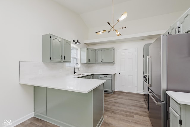 374 Pomona Ct, Greenfield, IN 46140 - kitchen featuring freestanding refrigerator, a peninsula, lofted ceiling, a sink, and a chandelier