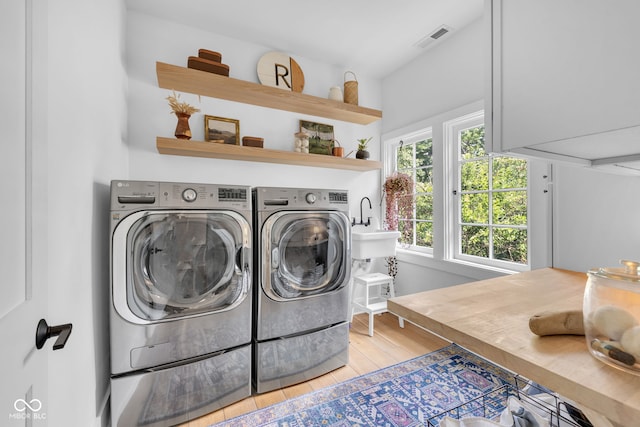 3215 N Pennsylvania St, Indianapolis, IN 46205 - laundry area with washing machine and dryer, light wood-style floors, and cabinet space