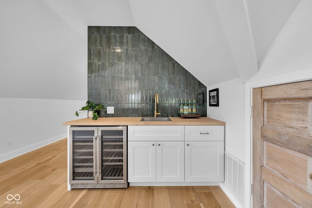 3215 N Pennsylvania St, Indianapolis, IN 46205 - indoor wet bar with beverage cooler, lofted ceiling, decorative backsplash, light wood-style floors, and baseboards
