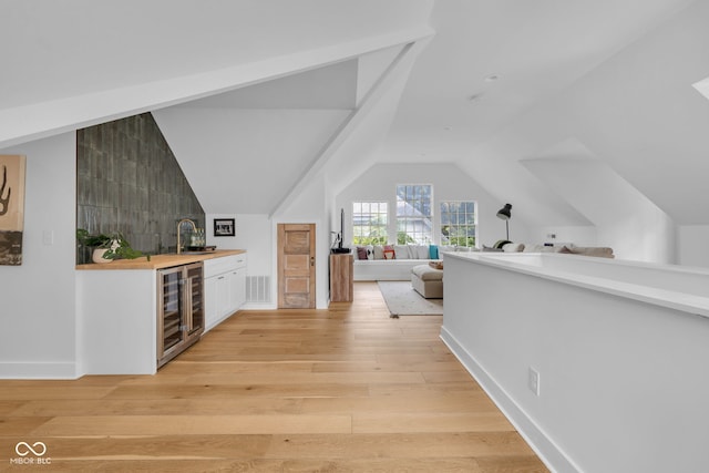 3215 N Pennsylvania St, Indianapolis, IN 46205 - indoor wet bar with beverage cooler, light wood-style floors, lofted ceiling, and baseboards