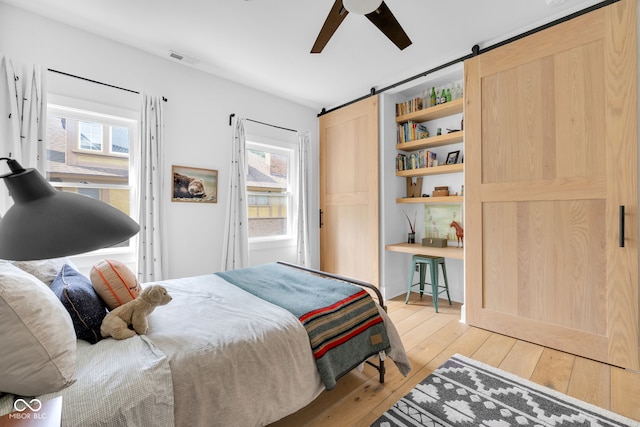 3215 N Pennsylvania St, Indianapolis, IN 46205 - bedroom with a barn door, light wood-type flooring, and a ceiling fan