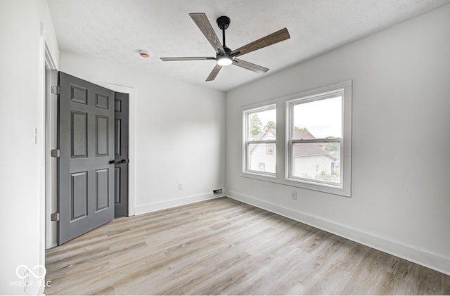 815 E 24th St E, Indianapolis, IN 46205 - unfurnished bedroom featuring light wood-type flooring, a textured ceiling, baseboards, and ceiling fan