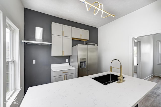 815 E 24th St E, Indianapolis, IN 46205 - kitchen with stainless steel fridge with ice dispenser, a sink, wall chimney exhaust hood, wood finished floors, and light stone countertops