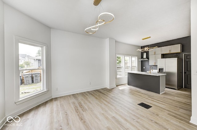 815 E 24th St E, Indianapolis, IN 46205 - kitchen with stainless steel refrigerator with ice dispenser, a chandelier, wall chimney range hood, light wood-type flooring, and a sink