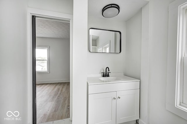 815 E 24th St E, Indianapolis, IN 46205 - bathroom with vanity, a textured ceiling, baseboards, and wood finished floors