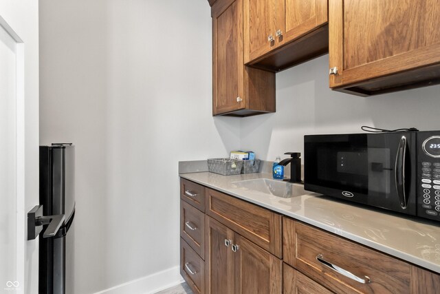 4808 Lakeview Dr, Greenwood, IN 46143 - kitchen featuring black microwave, a sink, light countertops, brown cabinets, and baseboards