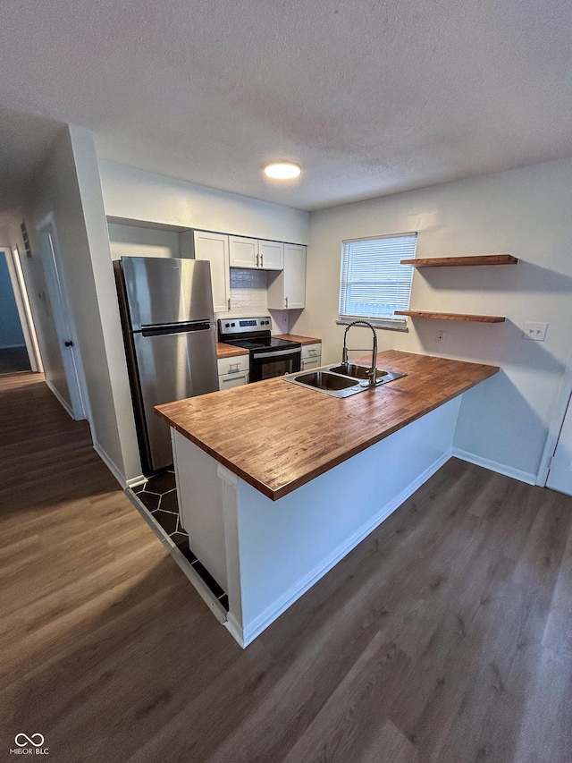 1653 Wade St, Indianapolis, IN 46203 - kitchen with appliances with stainless steel finishes, a sink, dark wood-type flooring, wooden counters, and a peninsula