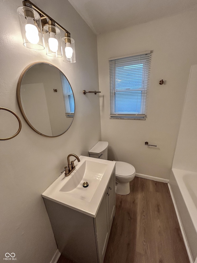 1653 Wade St, Indianapolis, IN 46203 - full bath with wood finished floors, toilet, vanity, baseboards, and a tub to relax in