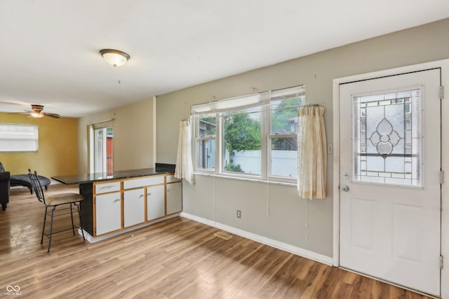 410 E Southport Rd, Indianapolis, IN 46227 - kitchen featuring a peninsula, dark countertops, light wood-type flooring, a kitchen bar, and a ceiling fan