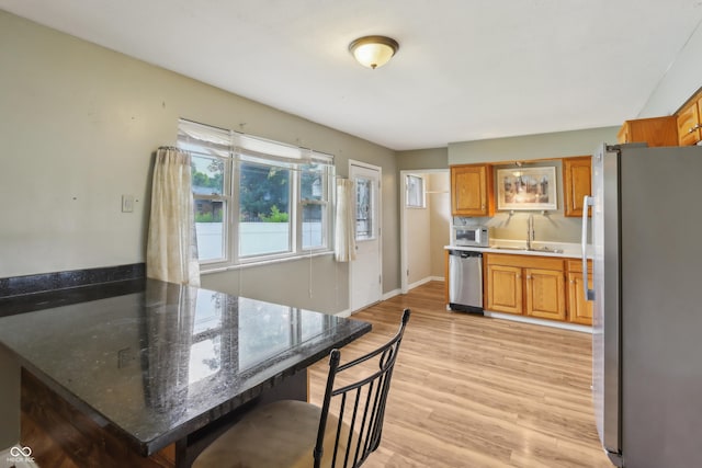 410 E Southport Rd, Indianapolis, IN 46227 - kitchen with stainless steel appliances, a sink, a peninsula, brown cabinetry, and light wood-type flooring