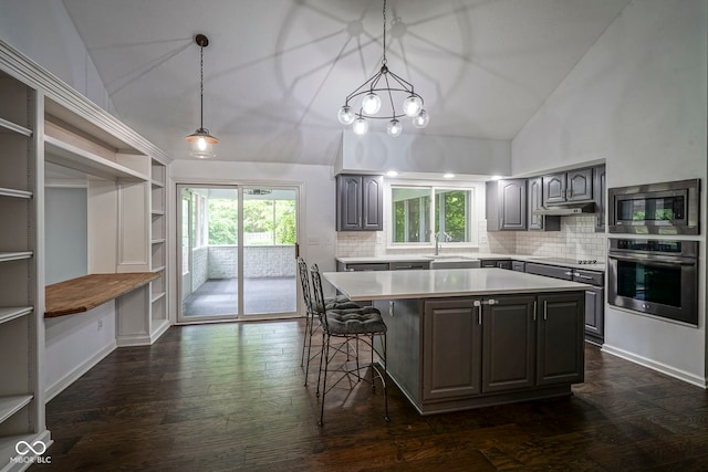 4949 Jennings Dr, Carmel, IN 46033 - kitchen featuring appliances with stainless steel finishes, light countertops, a kitchen island, under cabinet range hood, and decorative backsplash