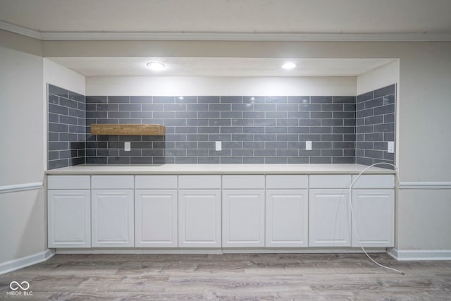 4949 Jennings Dr, Carmel, IN 46033 - kitchen with white cabinets, light countertops, light wood-style floors, tasteful backsplash, and ornamental molding