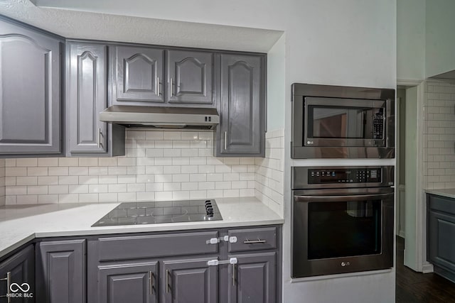 4949 Jennings Dr, Carmel, IN 46033 - kitchen with stainless steel appliances, under cabinet range hood, gray cabinets, light countertops, and decorative backsplash