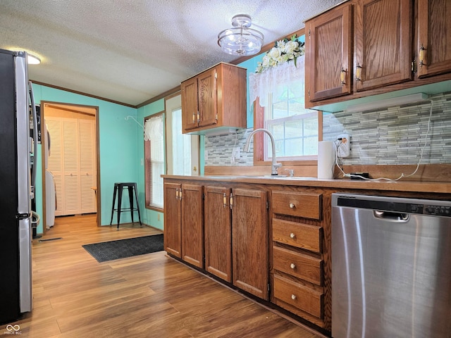 8310 Dog Trot Ln, Morgantown, IN 46160 - kitchen featuring appliances with stainless steel finishes, tasteful backsplash, vaulted ceiling, light wood-style flooring, and brown cabinets