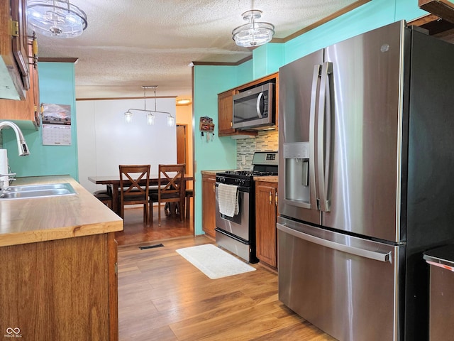 8310 Dog Trot Ln, Morgantown, IN 46160 - kitchen featuring appliances with stainless steel finishes, a sink, brown cabinetry, a textured ceiling, and decorative backsplash