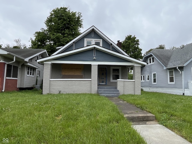 3526 Evergreen Ave, Indianapolis, IN 46205 - bungalow-style house with covered porch, a front lawn, a chimney, and brick siding