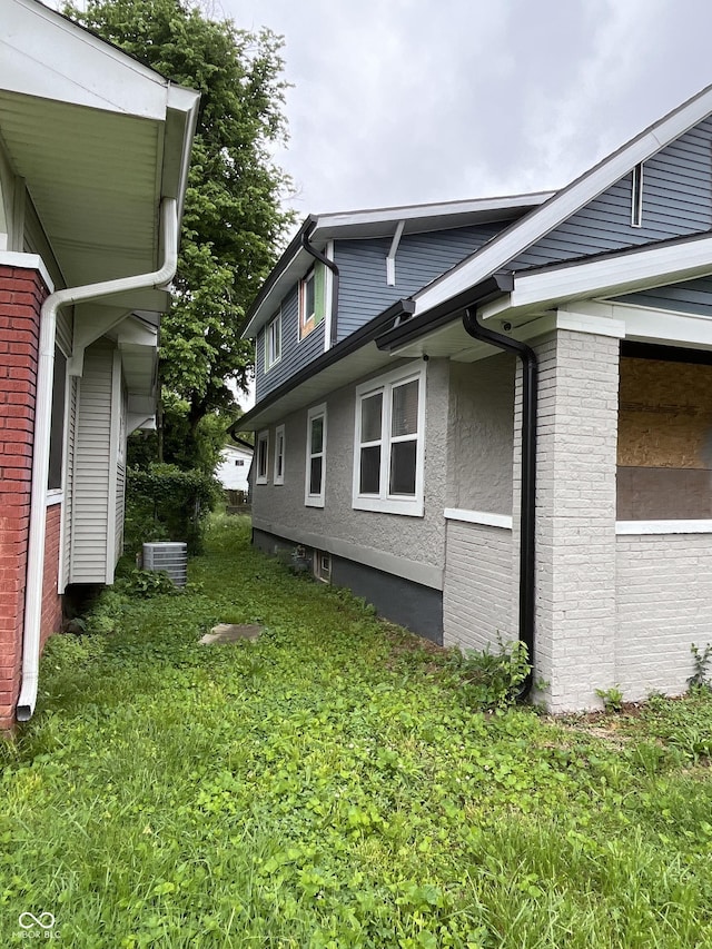 3526 Evergreen Ave, Indianapolis, IN 46205 - view of side of home with central air condition unit, stucco siding, and a yard