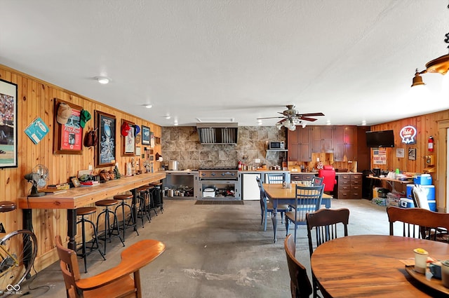 203 N Cross St, Hillsboro, IN 47949 - dining space featuring wooden walls, ceiling fan, and unfinished concrete floors