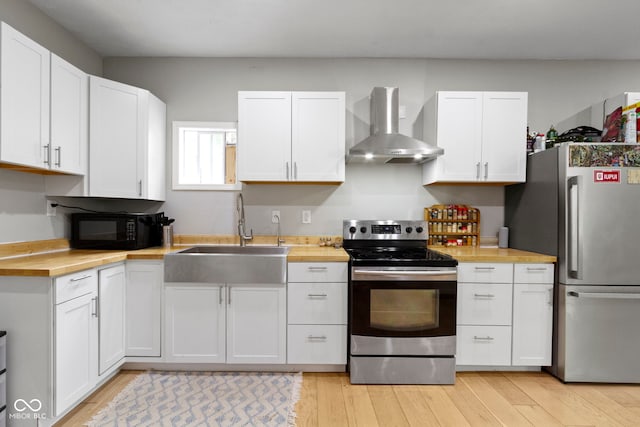 1150 W 30th St, Indianapolis, IN 46208 - kitchen with stainless steel appliances, wall chimney range hood, wood counters, a sink, and white cabinetry