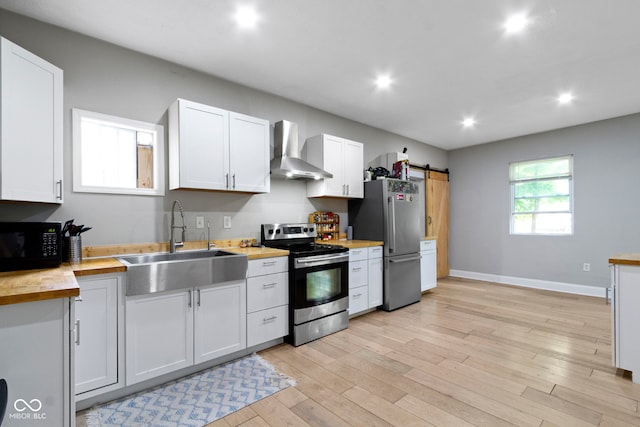 1150 W 30th St, Indianapolis, IN 46208 - kitchen with stainless steel appliances, wall chimney range hood, a sink, a barn door, and baseboards