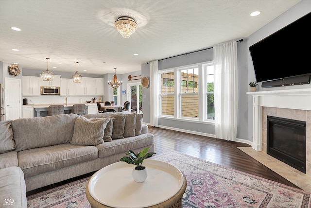 1071 Serenity Ct, Carmel, IN 46280 - living room featuring a chandelier, wood-type flooring, recessed lighting, a tiled fireplace, and baseboards
