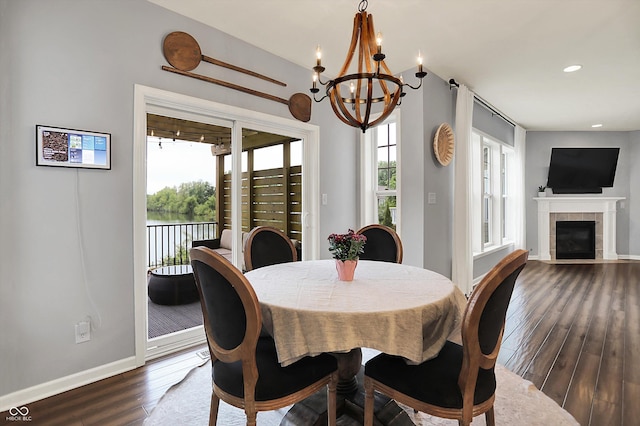 1071 Serenity Ct, Carmel, IN 46280 - dining room featuring dark wood-style flooring, a chandelier, a tiled fireplace, baseboards, and recessed lighting