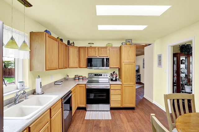 4125 S Post Rd, Indianapolis, IN 46239 - kitchen featuring appliances with stainless steel finishes, light wood-type flooring, a sink, a skylight, and light countertops