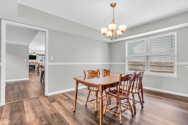 9754 Bradford Knoll Dr, Fishers, IN 46037 - dining room with a chandelier, wood finished floors, baseboards, and a stone fireplace