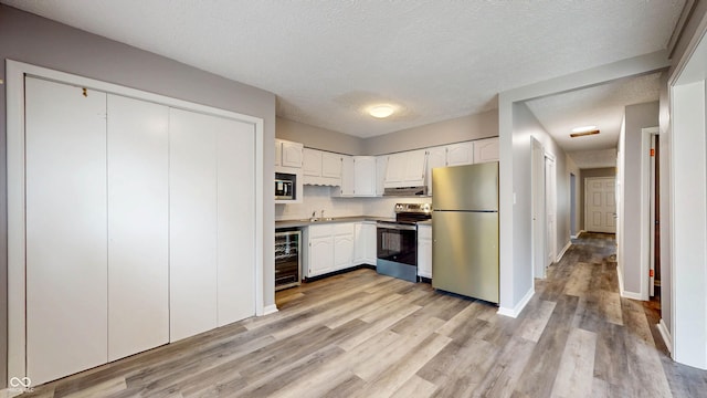 5806 E 19th St, Indianapolis, IN 46218 - kitchen with appliances with stainless steel finishes, beverage cooler, a sink, white cabinets, and a textured ceiling
