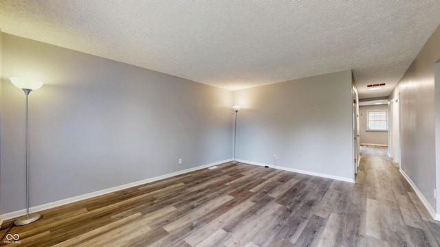 5806 E 19th St, Indianapolis, IN 46218 - spare room with wood finished floors, a textured ceiling, and baseboards