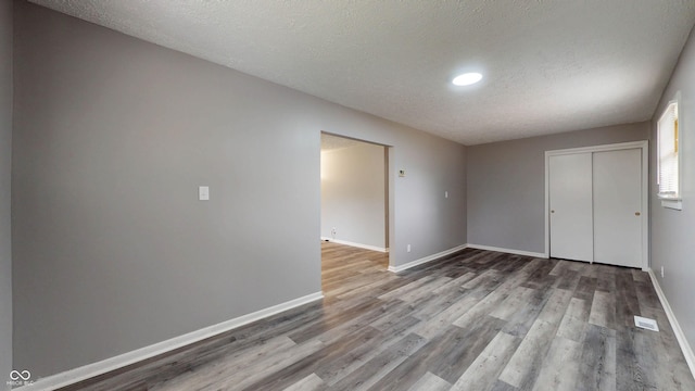 5806 E 19th St, Indianapolis, IN 46218 - unfurnished bedroom with wood finished floors, a closet, baseboards, a textured ceiling, and recessed lighting