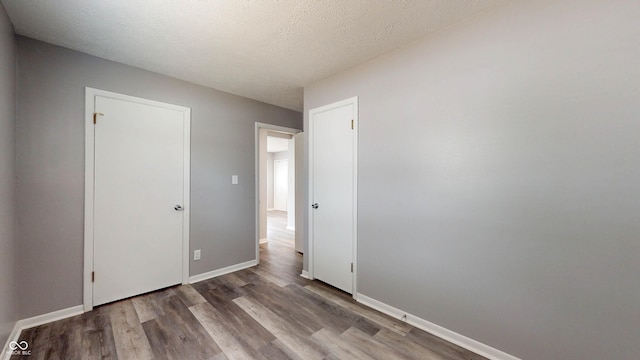 5806 E 19th St, Indianapolis, IN 46218 - unfurnished bedroom with wood finished floors, baseboards, and a textured ceiling