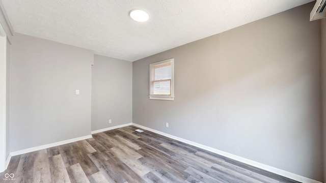 5806 E 19th St, Indianapolis, IN 46218 - spare room featuring wood finished floors, baseboards, and a textured ceiling