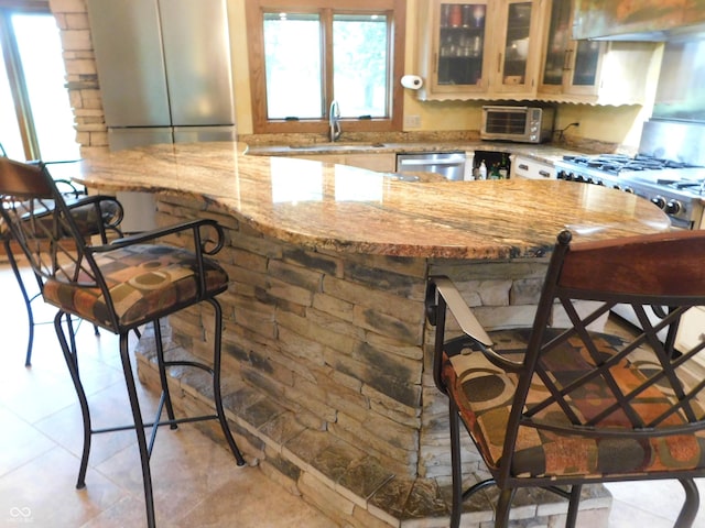 681 S County Road 150 W, Greensburg, IN 47240 - kitchen featuring a kitchen breakfast bar, stainless steel dishwasher, range hood, glass insert cabinets, and light tile patterned floors