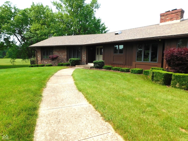 681 S County Road 150 W, Greensburg, IN 47240 - ranch-style house with a front lawn, a chimney, a shingled roof, brick siding, and board and batten siding