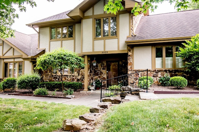 3935 Offshore Dr, Columbus, IN 47203 - english style home featuring stucco siding, roof with shingles, stone siding, and a front lawn