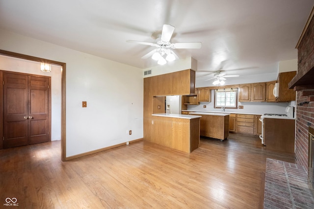 10244 Washington Blvd, Carmel, IN 46280 - kitchen with a peninsula, brown cabinetry, a ceiling fan, and light countertops